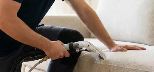 Professional upholstery cleaner deep-cleaning a fabric sofa with a handheld extraction tool, Bloomington, IN.